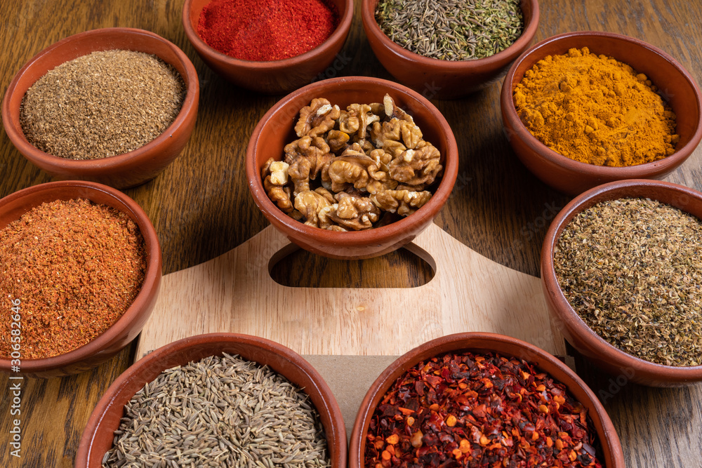 A selection of various colorful spices on a wooden table in bowls A selection of various colorful spices on a wooden table in bowls