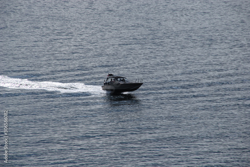 Light boat goes very quickly through the water to the sea on a summer sunny day