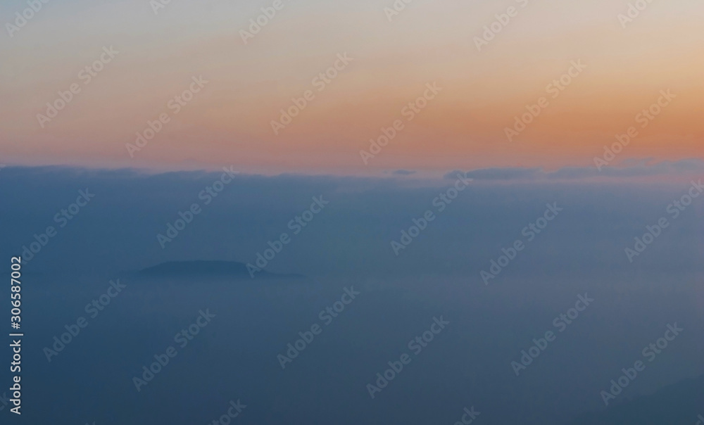 Blue mountains covered with solid fog  against a bright sunrise