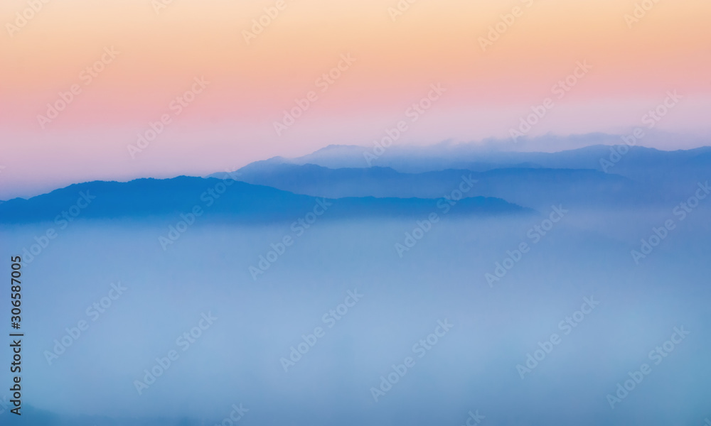 Blue mountains covered with solid fog on the background of the bright sunrise