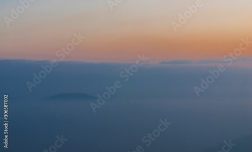 Blue mountains covered with solid fog against a bright sunrise