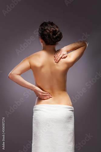 Young woman massaging back pain on gray background
