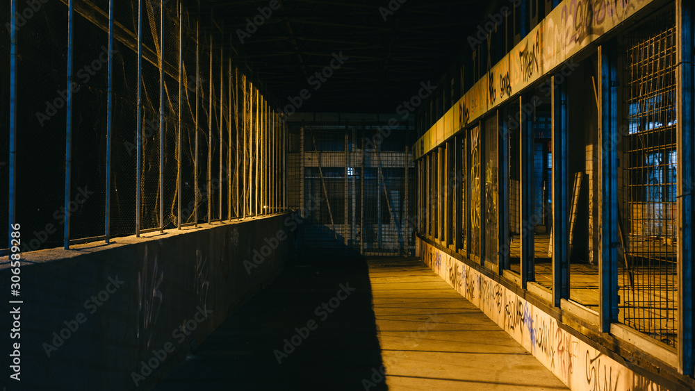 Grunge Dark Dirty Street with wired fence and yellow city lights leaking through sides with night light peaking through the sides. Grunge Dark Dirty Street with wired fence and yellow city lights leaking through sides with night light peaking through the sides.