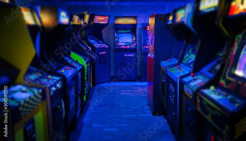 Foto Old Vintage Arcade Video Games in an empty dark gaming room with blue light with
