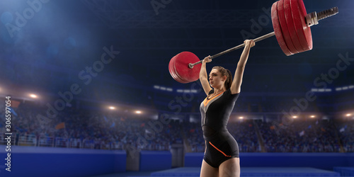 Female athlete is lifting a barbell on a professional stadium. Stadium and crowd are made in 3d.