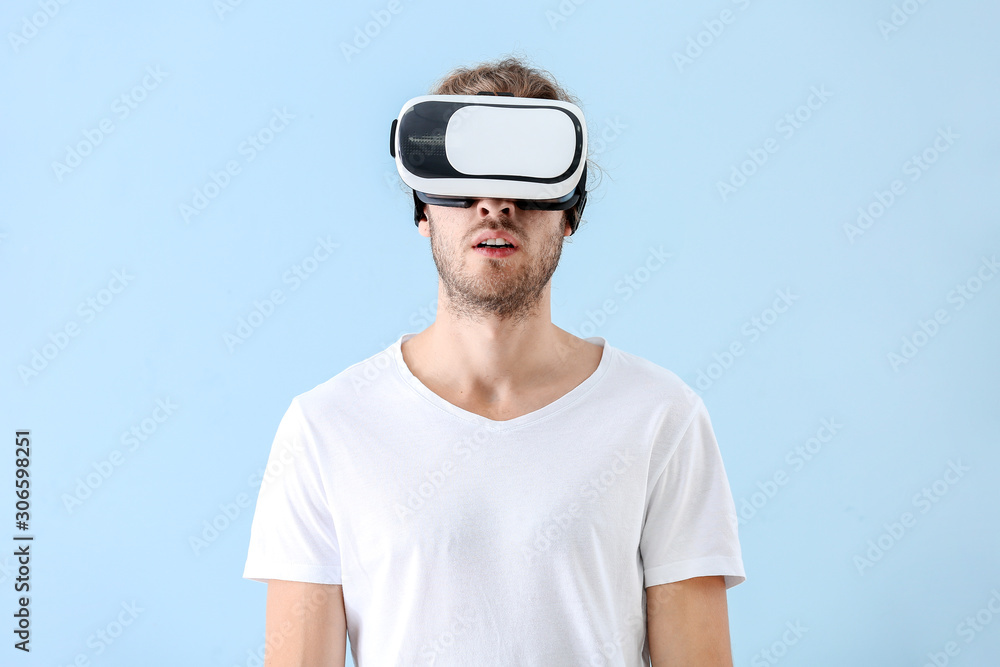 Young man with VR glasses on color background Young man with VR glasses on color background