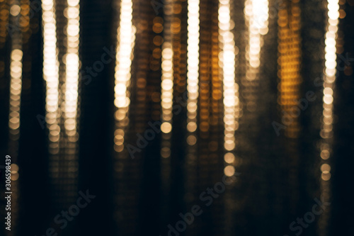 Golden shiny fabric with sequins, blured abstract background.