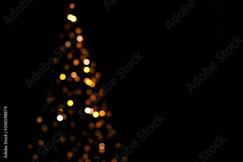 Lights of christmas tree blurred bokeh on dark background with copy space.