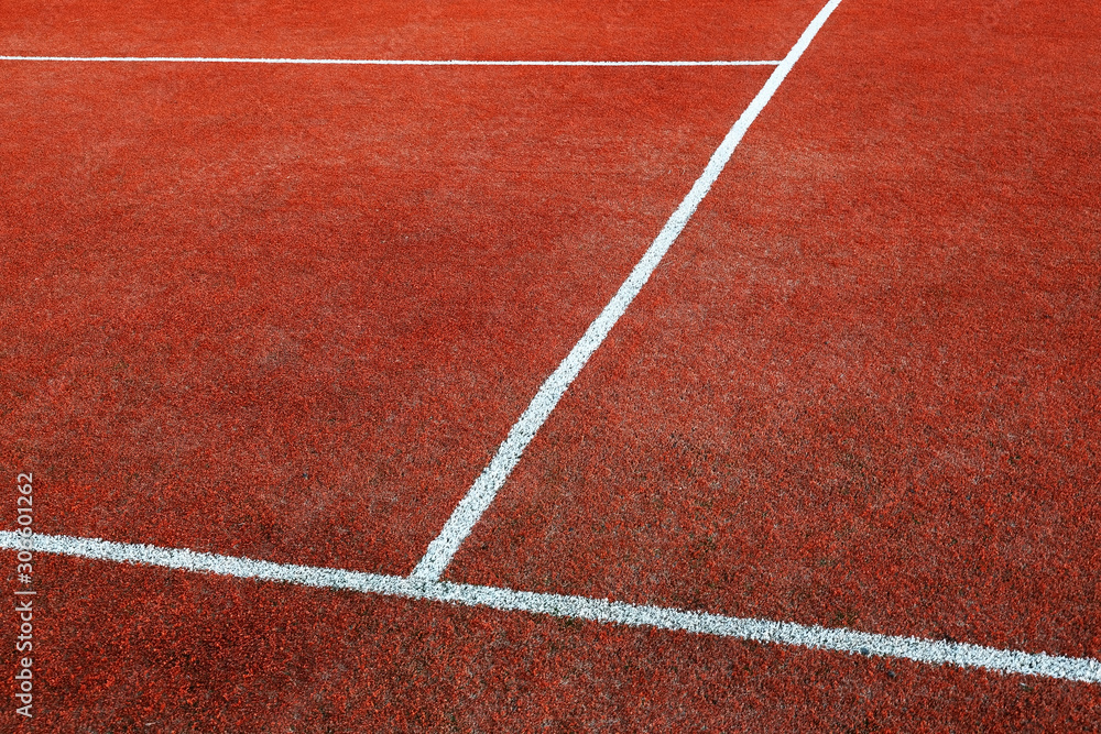 Part of empty used red tennis court playground surface with white lines closeup