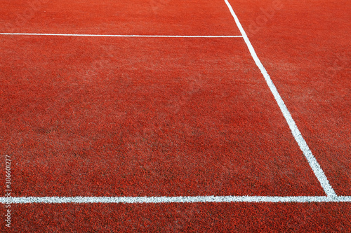 Part of empty used red tennis court playground surface with white lines closeup