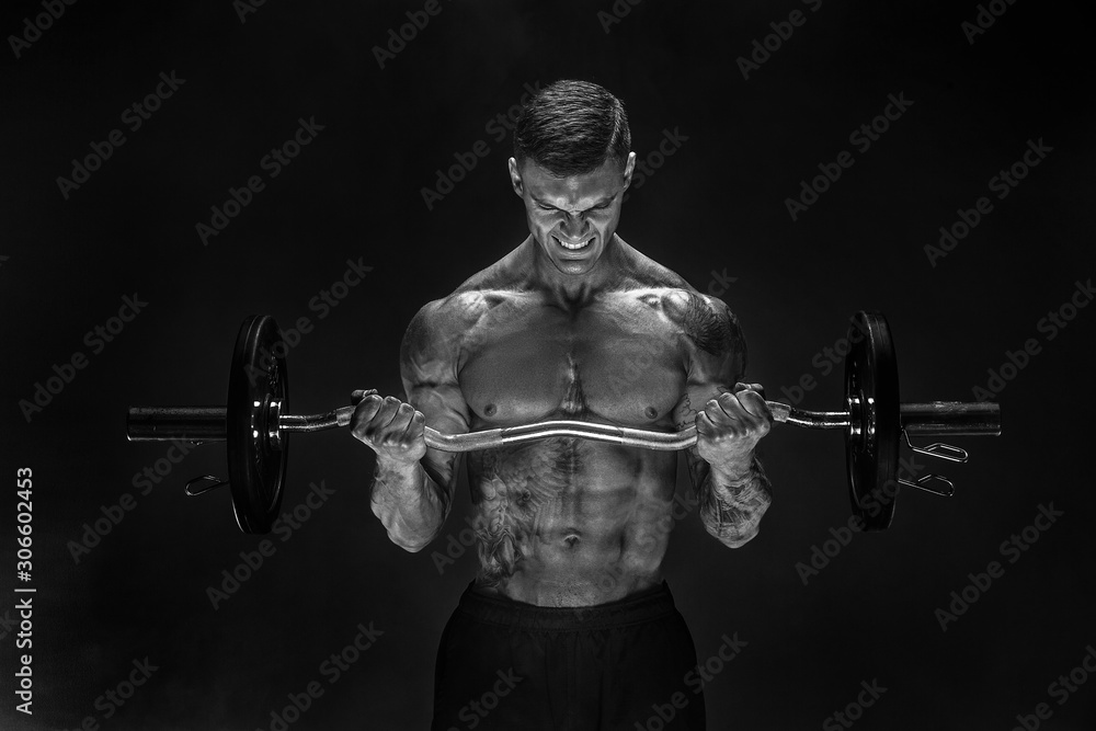 Studio portrait of topless bodybuilder performing biceps exercise with concentrated face over black background with smoke. Cutout. Very brawny guy bodybuilder. Studio portrait of topless bodybuilder performing biceps exercise with concentrated face over black background with smoke. Cutout. Very brawny guy bodybuilder.