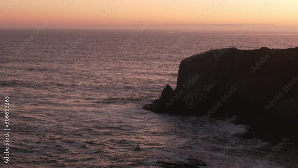 A rock protrudes into thehe purple waters of the Pacific Ocean at dusk along the Oregon coast. A rock protrudes into thehe purple waters of the Pacific Ocean at dusk along the Oregon coast.