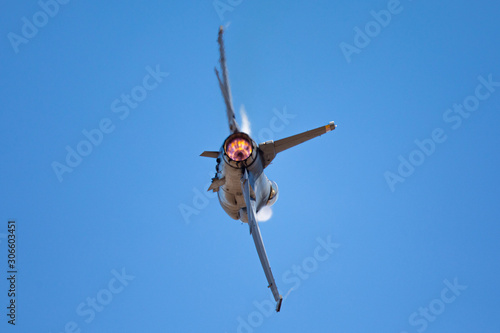 Extremely close view of a F-16 Fighting Falcon in a high G turn, with condensation streaks at the wing roots, with afterburner on 