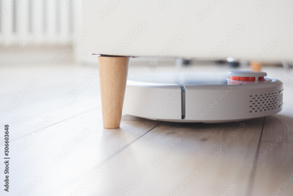 Robot vacuum cleaner vacuuming or hoovering under the bed Stock Photo |  Adobe Stock