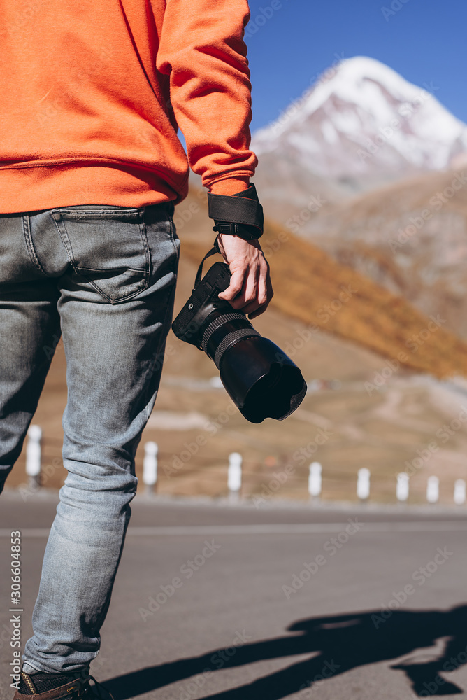 Close up, Yong man photographer holding digital camera DSLR with lens telephoto equipment for take a photo and picture memories travel landscape trip lifestyle. against Caucasus mountains background Close up, Yong man photographer holding digital camera DSLR with lens telephoto equipment for take a photo and picture memories travel landscape trip lifestyle. against Caucasus mountains background