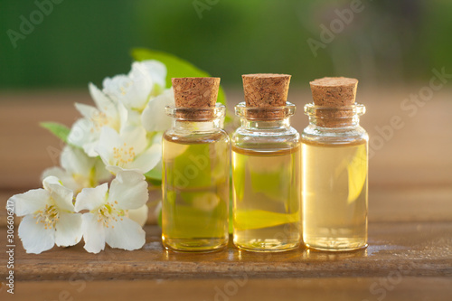 Essence of flowers on wooden background in beautiful glass jar