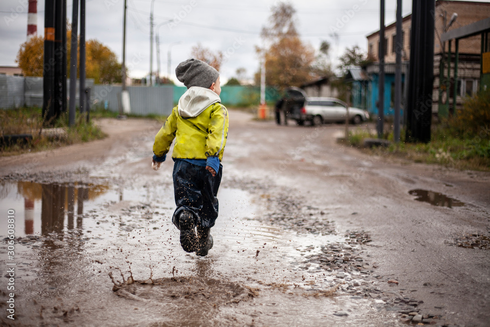 The boy runs through the puddles. Disobedient child The boy runs through the puddles. Disobedient child