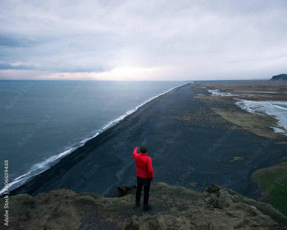 hombre arriba de la colina mirando al mar en islandia