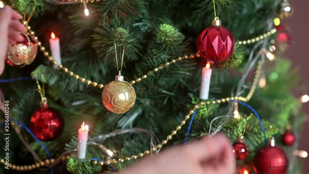 Children's hands decorate the Christmas tree in the room with decorative balls. Preparing for Christmas and New Year. Holidays Children's hands decorate the Christmas tree in the room with decorative balls. Preparing for Christmas and New Year. Holidays