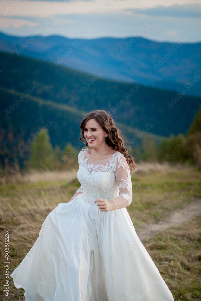 Beautiful wedding couple, bride and groom, in love on the background of mountains. The groom in a beautiful suit and the bride in a white luxury dress. Wedding couple is walking