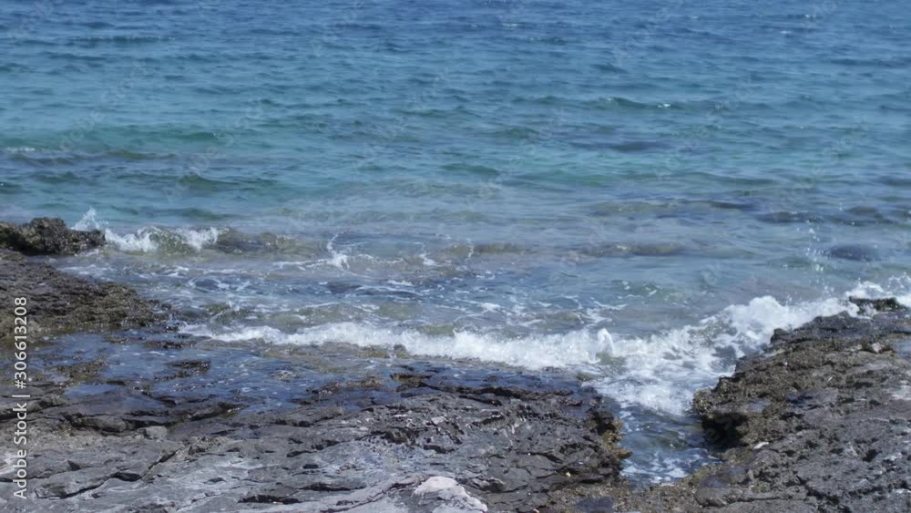 View on the rocky shore with a seagull flying by. Waves smashing the rocks. Steady slow motion camera shot. View on the rocky shore with a seagull flying by. Waves smashing the rocks. Steady slow motion camera shot.