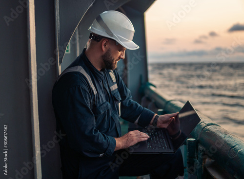 Photo Marine chief officer or captain on deck of vessel or ship watching laptop