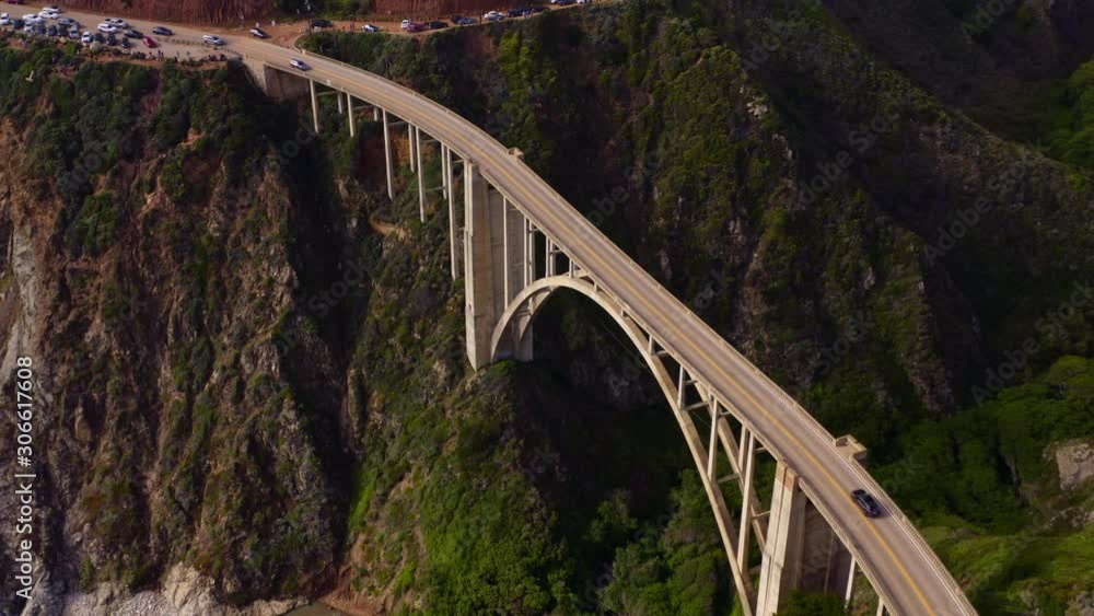 Aerial topdown survey over the high narrow concrete construction of Bixby Bridge crossing the creek on the coastline of Pacific Ocean and being a part of scenic coastal route. 4K Aerial topdown survey over the high narrow concrete construction of Bixby Bridge crossing the creek on the coastline of Pacific Ocean and being a part of scenic coastal route. 4K