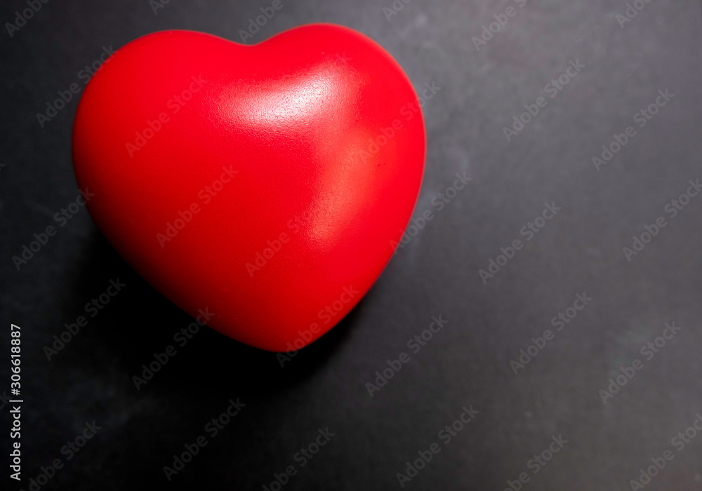 Obraz premium Top view. The red heart on a black background with white light shines down to the heart.