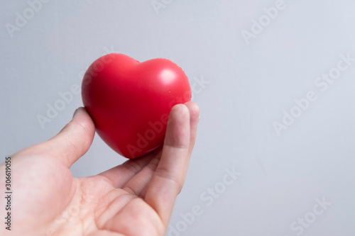 Fototapeta Naklejka Na Ścianę i Meble -  One red heart was hand in one hand. Take care of your health and heart.