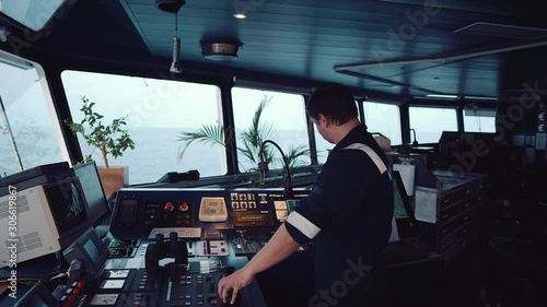 Marine navigational officer during navigational watch on Bridge . He is maneuvering the ship. Work at sea. photo