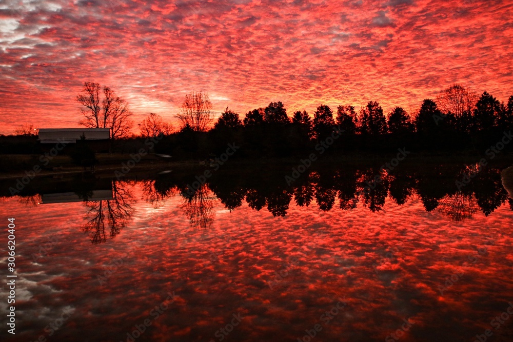 Dramatic red colored sunrise over a serene country pond Dramatic red colored sunrise over a serene country pond