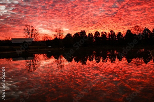 Dramatic red colored sunrise over a serene country pond