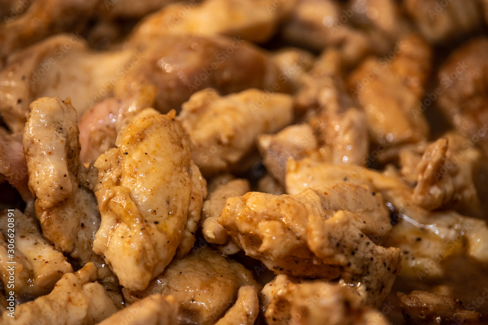 Marinated torn cut chicken bits being cooked, halfway cooked. Spicy chicken, wooden spatula Marinated torn cut chicken bits being cooked, halfway cooked. Spicy chicken, wooden spatula