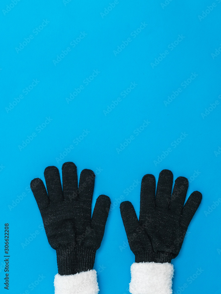 Obraz premium Knitted black women's gloves bottom blue background. The concept of hope and meeting.