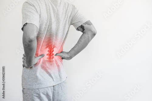 Office syndrome, Backache and Lower Back Pain Concept. a man touching his lower back at pain point photo