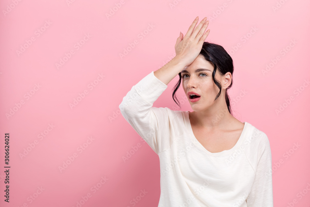 Young woman making a mistake on a pink background Young woman making a mistake on a pink background