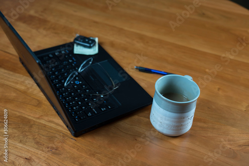 Cup of coffee on wood office desk with black laptop