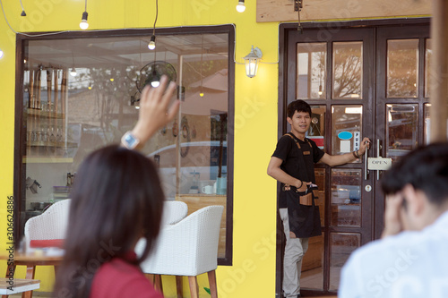 portrait of handsome asian man waving his hands to his friends while walking into them