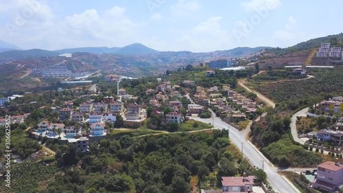 Stunning aerial view of the houses on the hill with blue cloudy sky on the background. Art. Cottages and villas located on the slope of green forested mountain. photo