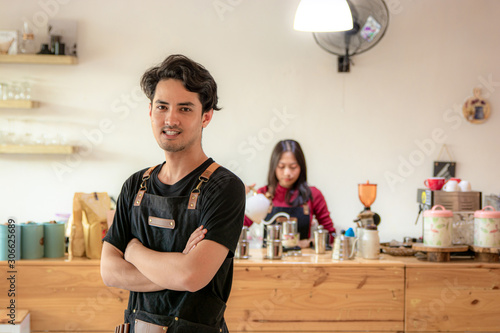 Portrait of a smiling young Asian male entrepreneur standing with her arms crossed
