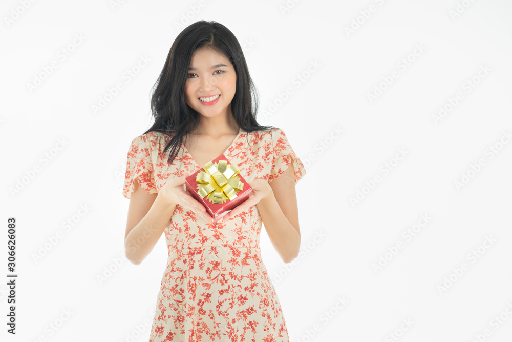 Photo of asian curious woman in red dress rejoicing her birthday or new year gift box. Young woman holding gift box with red bow being excited and surprised holiday. Photo of asian curious woman in red dress rejoicing her birthday or new year gift box. Young woman holding gift box with red bow being excited and surprised holiday.