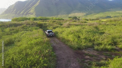 Drone shot following modern pick up truck through dirt off road trail in Hawaii photo