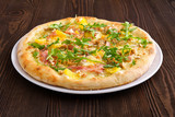 Pizza with turkey, bacon, orange and cashew nuts on dark wooden background