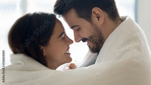 Beautiful happy couple bonding laughing covered with warm blanket