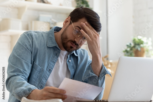 Upset frustrated young man holding reading postal mail letter