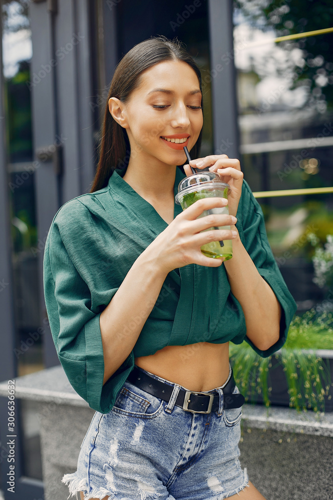 Beautiful girl in a city. Stylish brunette in a green blouse. Lady with a cocktail Beautiful girl in a city. Stylish brunette in a green blouse. Lady with a cocktail