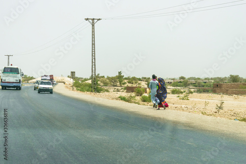 a man is walking along with his family  on the side of road cause of extreme poverty and lack of transportation 