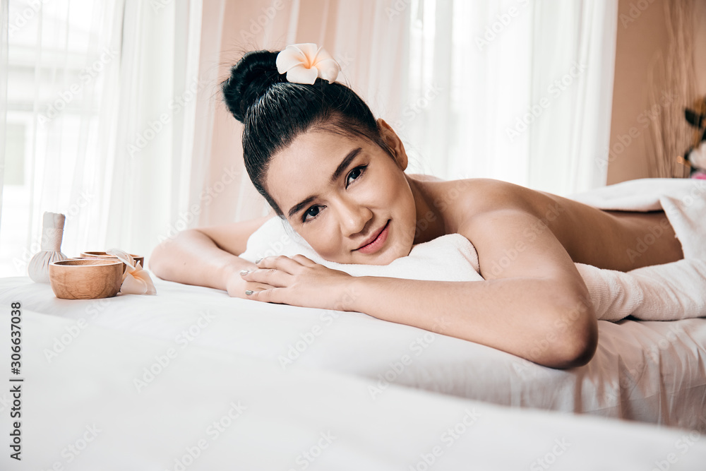 Beautiful Asian woman Relaxing On Massage Table and Smiling At Camera Beautiful Asian woman Relaxing On Massage Table and Smiling At Camera