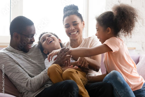 Overjoyed biracial family with kids have fun at home