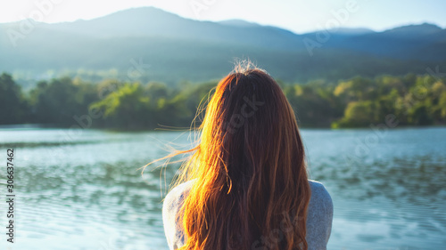 Canvas Print A woman sitting alone by the lake looking at the mountains with green nature bac